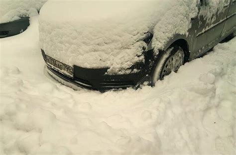 Vairuotojas valo automobilio langą nuo sniego ir ledo