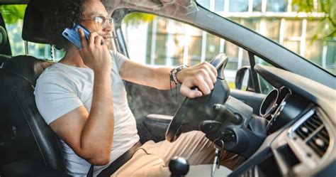 Teminė nuotrauka su automobiliu ir vairuotoju, naudojančiu telefoną