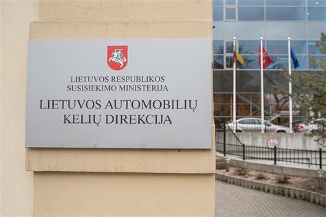 Teminis paveikslėlis: grupė žmonių, mokymų metu dirbančių su kompiuteriais, fone - Lietuvos automobilių kelių direkcijos logotipas