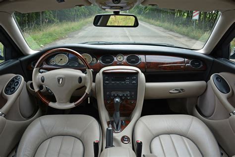 Nuotrauka, vaizduojanti Rover 75 salono interjerą su medžio apdaila ir veliūro sėdynėmis.