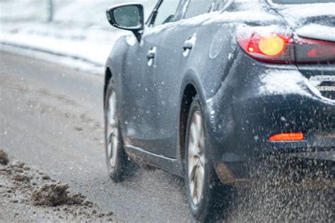Automobilis apsnigtame kelyje žiemą, demonstruojantis atšiaurių oro sąlygų įtaką