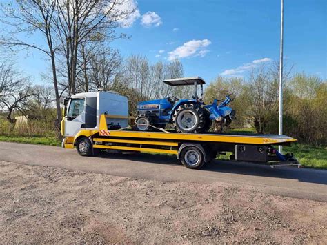 Sunkvežimis su platforma (tralas) transportuojantis automobilį kelyje