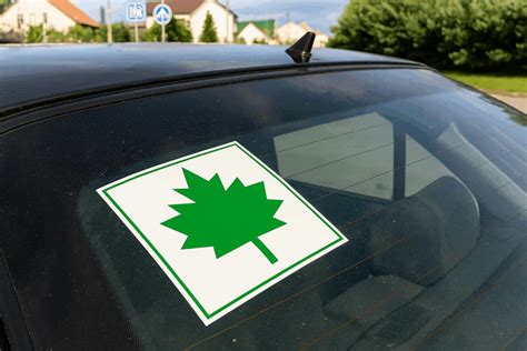 Teminis paveikslėlis, vaizduojantis jauną žmogų su „klevo lapu“ ant automobilio