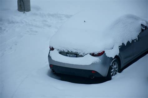 automobilis žiemą, padengtas sniegu, pastatytas prie namo