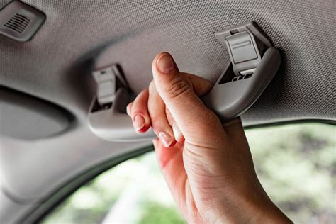 Tematinė nuotrauka: žmogus spaudžia automobilio kapotą virš užrakto, o kitas asmuo traukia rankenėlę salone.