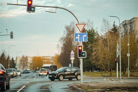 automobiliai sankryžoje su šviesoforu ir kelio ženklais