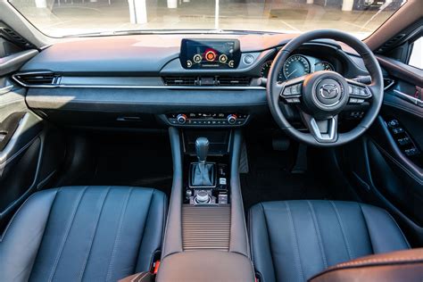 The interior of a Mazda 6 car with a detailed view of the gear shift knob and surrounding console.