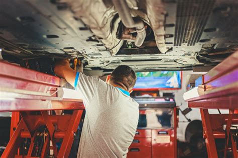 Mechanikas apžiūri automobilio pusašį ant keltuvo