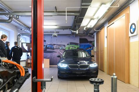 Nuotrauka, kurioje matyti moderni mokomoji „BMW laboratorija“ su hibridiniu automobiliu ir diagnostine įranga.