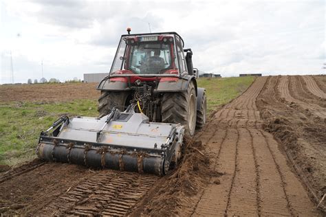 Nuotrauka japoniško mini traktoriaus su sumontuota freza, demonstruojanti jo kompaktiškumą ir darbo našumą.