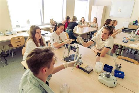 Teminė nuotrauka su studentais, dirbančiais su elektros įranga laboratorijoje