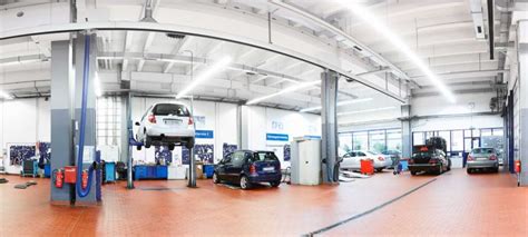 Tematinė nuotrauka su autoserviso darbuotojais dirbančiais su automobiliais.