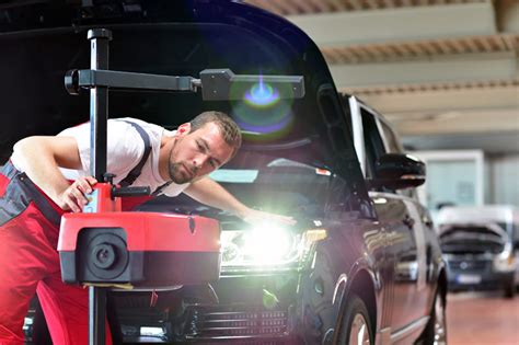 Autoserviso meistras, reguliuojantis automobilio žibintus specialia įranga
