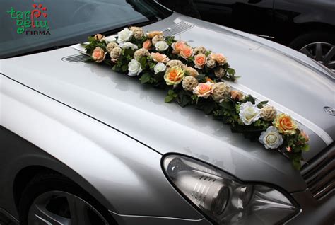 Jaunavedžių pora šalia vestuvinio automobilio