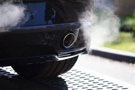 Tematinė iliustracija su automobiliais ir CO2 išmetimo simboliais