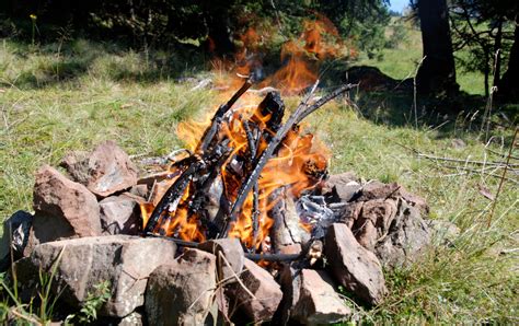 Saugiai įrengtos laužavietės schema: akmenimis sutvirtintas kraštas, pašalinta žolė, aplink esanti mineralizuota zona