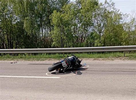 Motociklininkas su keleiviu šalmais važiuoja keliu, pabrėžiant saugumą
