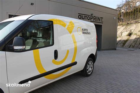 Nuotrauka, demonstruojanti profesionalų procesą, kai meistras kruopščiai klijuoja tamsinimo plėvelę ant automobilio lango