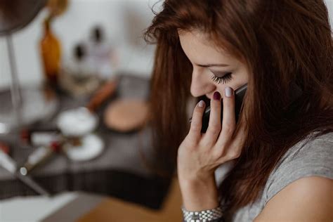 Asmuo, žiūrintis į neveikiantį mobiliojo ryšio telefoną, su ryšio bokštais fone