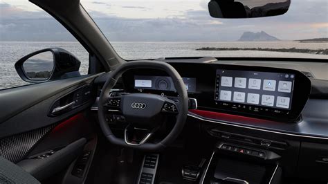 Audi automobilio interjero vaizdas, akcentuojantis pažangias technologijas, didelius ekranus ir minimalistinį dizainą