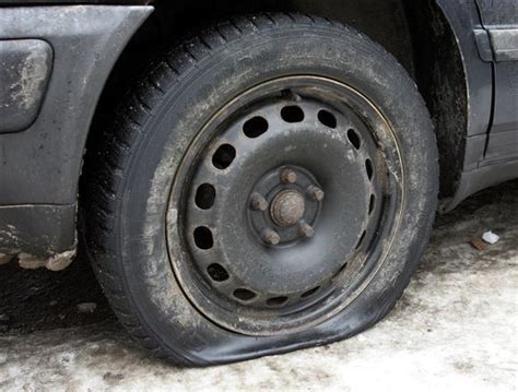 Teminė nuotrauka su automobiliu ir pradurta padanga kelyje