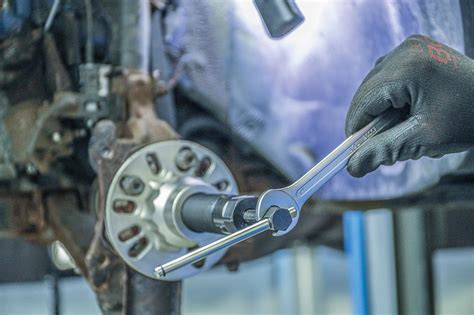 Tematinė nuotrauka: mechanikas, dirbantis su hidrauliniu transmisijos keltuvu po automobiliu