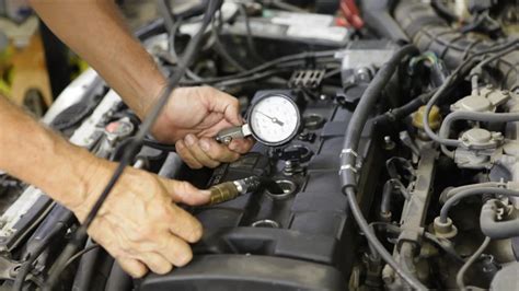 Mechanikas atlieka variklio kompresijos testą garaže