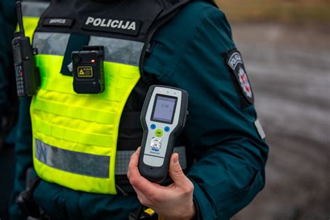 Teminė nuotrauka, vaizduojanti alkotesterį ir policijos pareigūną