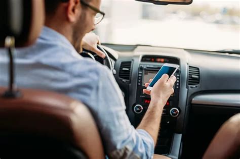 Tematinė nuotrauka, vaizduojanti asmenį, kalbantį telefonu automobilyje per laisvų rankų įrangą