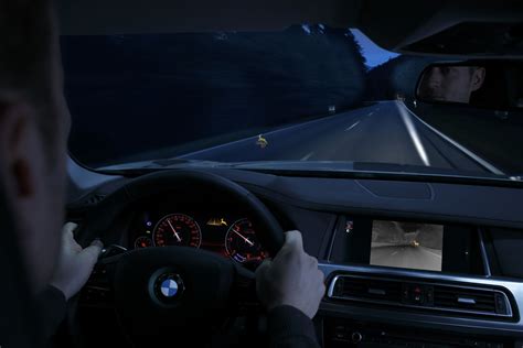Teminė nuotrauka, vaizduojanti automobilį važiuojantį naktį su įjungta naktinio matymo sistema.