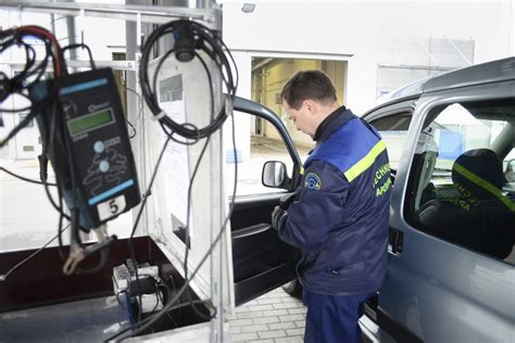 automobilis ant techninės apžiūros stendo, kontrolierius tikrina ratus