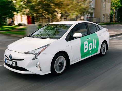 Bolt taksi automobilis, stovintis mieste, su programėle telefone