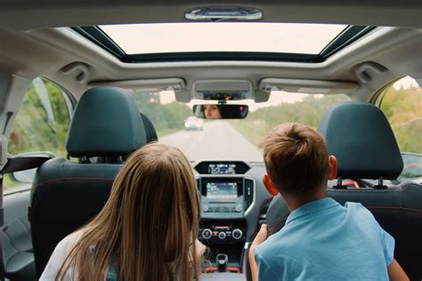 Teminė nuotrauka: besišypsanti pora sėdi nuomotame automobilyje, keliaujanti vaizdingu užsienio keliu
