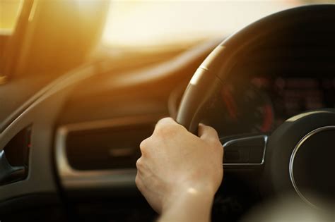 Vairuotojas, sėdintis prie automobilio vairo, su neaiškiu žvilgsniu.