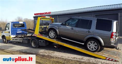 Tralas su automobiliu ant platformos, paruoštas transportavimui
