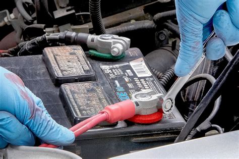 Thematic photo of car battery maintenance, including checking electrolyte levels and terminal cleaning