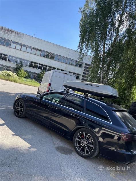 Toyota automobilis su sumontuota stogo bagažine ir dviračių laikikliu
