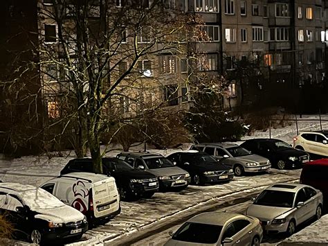 Teminė nuotrauka, atspindinti automobilių stovėjimo aikštelės trūkumą prie daugiabučio.