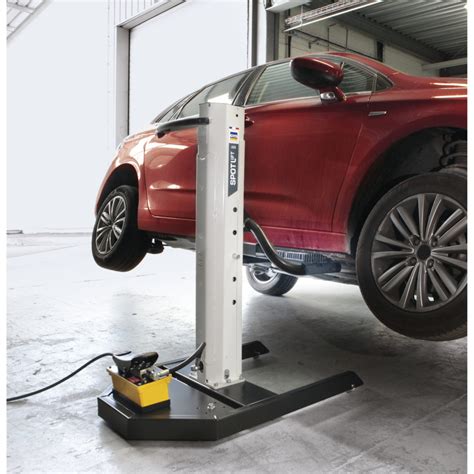 Tematinė nuotrauka su automobiliu, kuris yra pakeltas GYS SPOT Lift PRO keltuvu ir darbuotojas atlieka remonto darbus