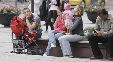 Tėvai su vaikais dviračio priekaboje, važiuojantys parku