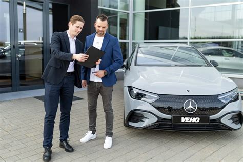 Tematinė nuotrauka: Laimingas klientas, atsiimantis naują automobilį automobilių salone, su vadybininku