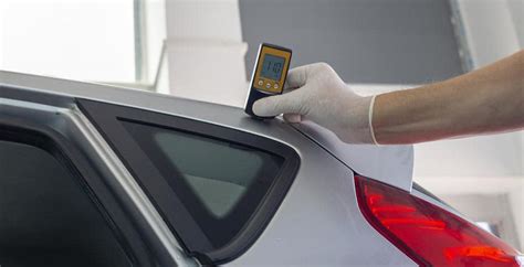 Specialistas tikrina automobilio kėbulo dažų sluoksnį naudojant storio matuoklį