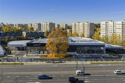 Modernių automobilių salonas su klientais, apžiūrinėjančiais naujus modelius