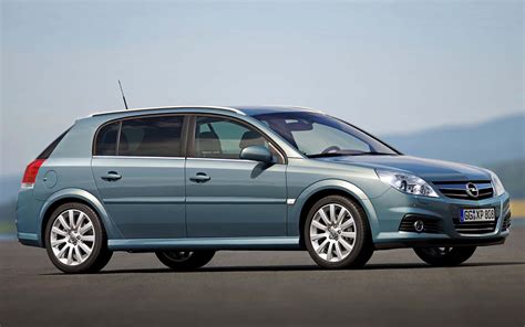 The sleek profile of an Opel Signum driving on a scenic highway, highlighting its extended wheelbase and unique hatchback rear design.