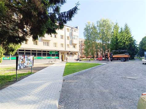 Daugiabučio kiemas, kuriame gausu stovinčių automobilių, pėsčiųjų takai ir žalia zona