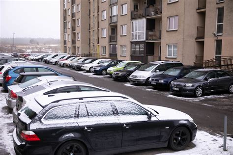 Nuotrauka, kurioje matomas apgadintas automobilis daugiabučio kieme, su įlenktomis durelėmis