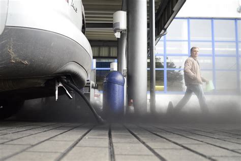 Tematinė nuotrauka: automobilis su dūmais ir aplinkosaugininkas matuoja taršą