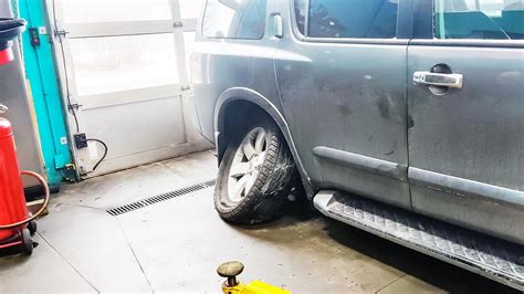 nuotrauka, kurioje matomas meistras tikrinantis automobilio pakabą