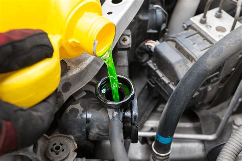 Mechanikas tikrina automobilio aušinimo skysčio lygį ir spalvą