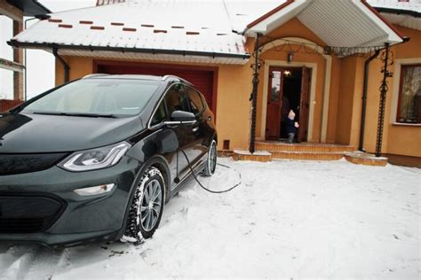 Teminė nuotrauka, vaizduojanti automobilį su įjungtu varikliu daugiabučio kieme žiemos metu